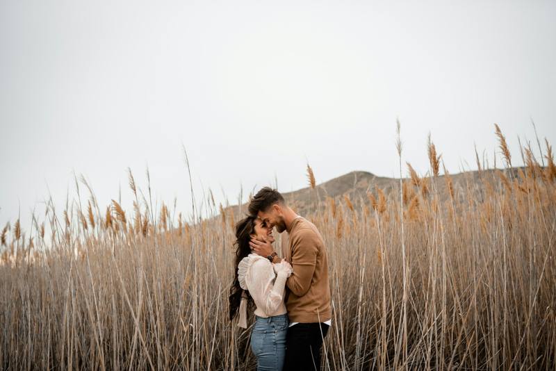 A man and a woman standing in a field of tall grass
