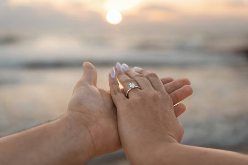 Couple's hands with engagement ring at sunset