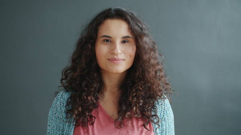 A young woman with curly hair smiles