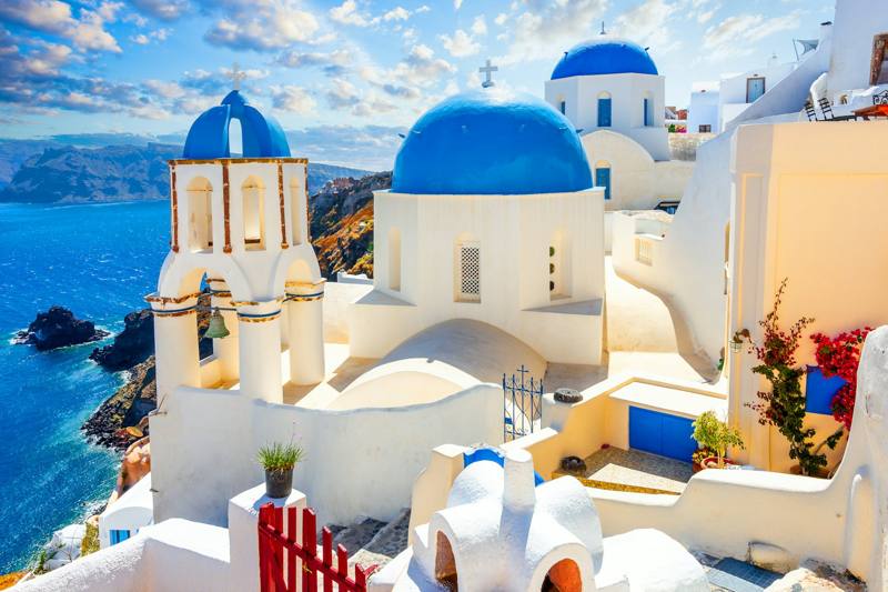 White buildings with blue domes overlook the ocean in santorini